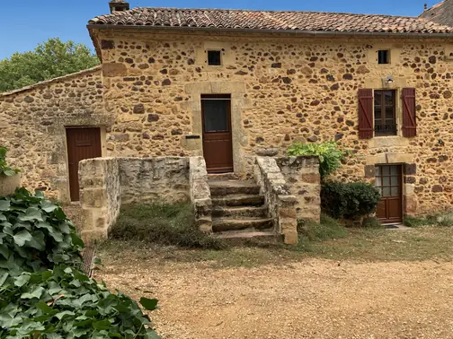 La façade en pierre de Lou Cantou sous les arbres