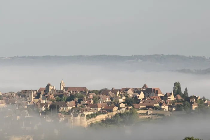 La bastide de Domme émergeant de la brume matinale, au-dessus de la vallée de la Dordogne