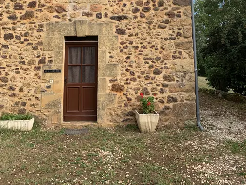 La façade en pierre du Pigeonnier, sa fenêtre et sa porte d'entrée